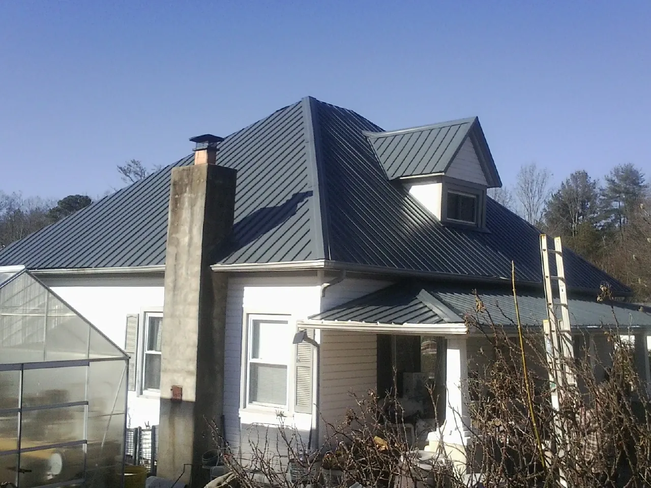 Dark blue standing seam metal roof on a white farmhouse with dormer — Slate & Tile Roof Repair by Roofing Brothers in Scranton