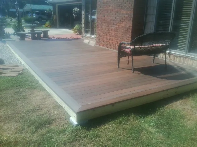 New wood deck and wicker chair beside a brick house in Scranton